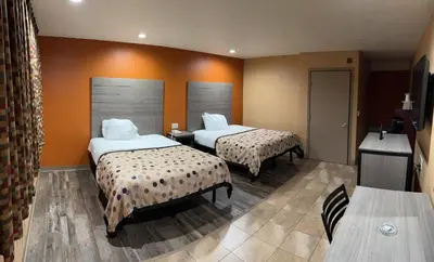 a hotel room with two beds and a television at Apex Inn in Modesto