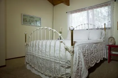 a white bed in a room with a window at Lovely Mountain Lake Chalet by Yosemite: Equipped! in Groveland