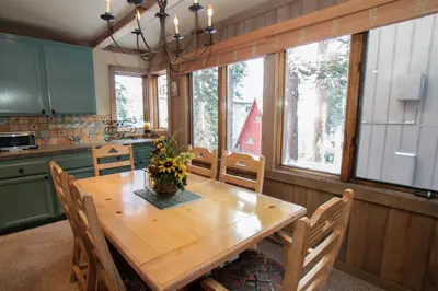 a kitchen with a wooden table and some windows at Mountainback 48 Corner Unit in Mammoth Lakes