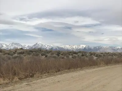 a dirt road with snow capped mountains in the distance at Mountainback 37 Den in Mammoth Lakes