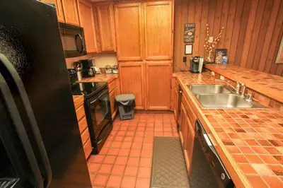 a kitchen with wooden cabinets and a sink and a refrigerator at Mountainback 73 Den in Mammoth Lakes