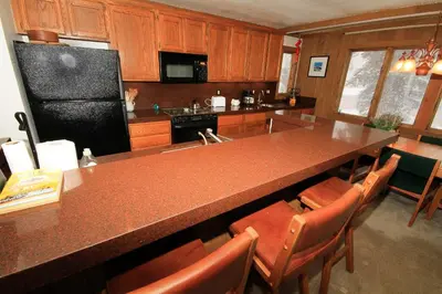 a kitchen with a large counter and a black refrigerator at Mountainback 72 Corner Unit in Mammoth Lakes