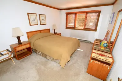 a bedroom with a bed and two tables and a window at Mountainback 72 Corner Unit in Mammoth Lakes