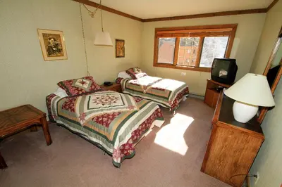 a bedroom with two beds and a tv and a lamp at Mountainback 60 Corner Unit in Mammoth Lakes