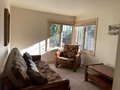 a living room with a couch and a chair and windows at Mountainback 57 Den in Mammoth Lakes