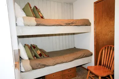 a room with two bunk beds with pillows and a chair at Discovery 4 113 in Mammoth Lakes