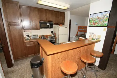 a kitchen with wooden cabinets and a counter with stools at Crestview 17 in Mammoth Lakes