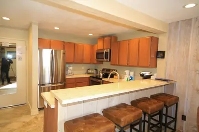 a kitchen with wooden cabinets and a counter with bar stools at Mammoth Ski Racquet Club 86 - Pet Friendly in Mammoth Lakes