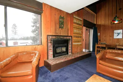 a living room with a fireplace and two leather chairs at Mammoth Ski Racquet Club 129 in Mammoth Lakes