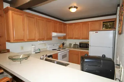 a kitchen with wooden cabinets and a white refrigerator at Mammoth Ski Racquet Club 120 - Pet Friendly in Mammoth Lakes