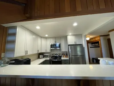 a kitchen with white cabinets and a stainless steel refrigerator at Mountainback 115 3 bedroom loft in Mammoth Lakes