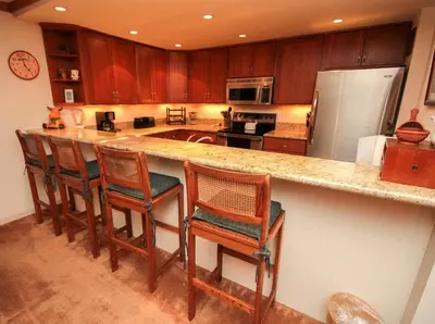 a kitchen with a counter with chairs and a refrigerator at Mountainback 111 in Mammoth Lakes