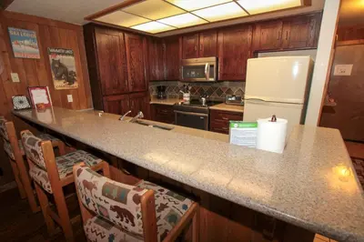 a kitchen with a counter with chairs and a refrigerator at Mountainback 105 Loft Den in Mammoth Lakes