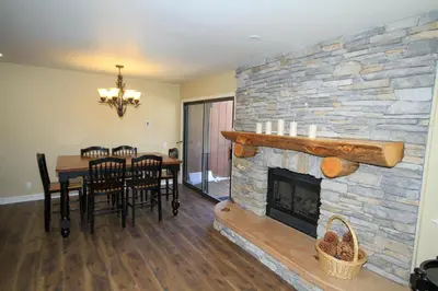 a living room with a stone fireplace and a table and chairs at Mammoth Ski Racquet Club 12 - Pet Friendly in Mammoth Lakes