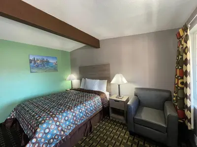 a small hotel room with a bed and a chair at Travel Inn in South Lake Tahoe