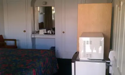 a room with a refrigerator and a bed and a mirror at San Joaquin Motel in Merced