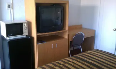 a small room with a tv and a bed at San Joaquin Motel in Merced