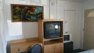 a tv on a wooden stand with a painting on the wall at San Joaquin Motel in Merced