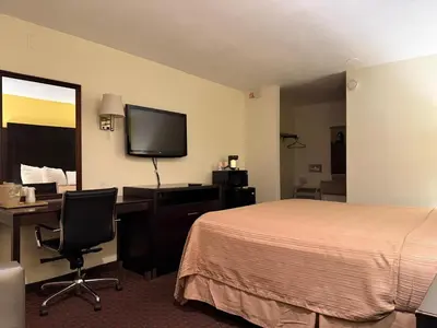 a hotel room with a bed and a desk and a tv at Hollister Inn in Hollister
