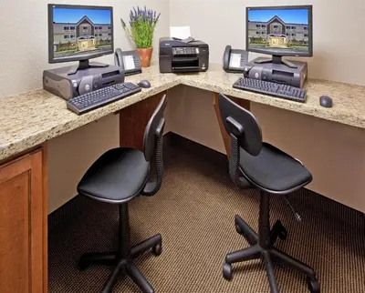 a desk with two computer monitors and two chairs at Candlewood Suites Turlock by IHG in Turlock