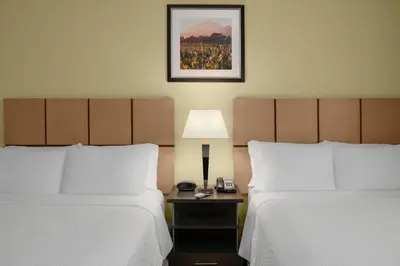a hotel room with two beds and a table with a lamp at Candlewood Suites Turlock by IHG in Turlock
