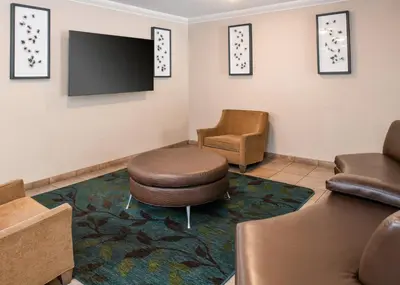a waiting room with a flat screen tv and chairs at Candlewood Suites Turlock by IHG in Turlock