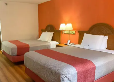 two beds in a hotel room with orange walls at Motel 6-Westley, CA in Westley