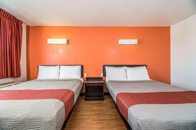 two beds in a room with an orange wall at Motel 6-Westley, CA in Westley