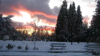 a picnic table in a snow covered park with the sunset at Westhaven Inn Pollock Pines Camino in Pollock Pines
