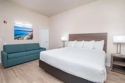 a bedroom with a large bed and a blue couch at Westhaven Inn Pollock Pines Camino in Pollock Pines