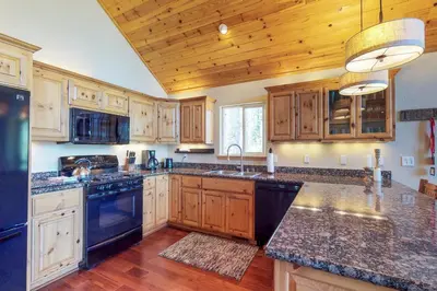 a large kitchen with wooden cabinets and black appliances at Wooded Escape in Donner Pines Tract