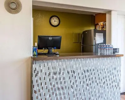a counter with a computer and a clock on the wall at Rodeway Inn Downtown Hanford in Hanford