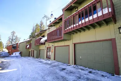 a house with two garage doors on a snowy street at Courchevel 51 in Mammoth Lakes