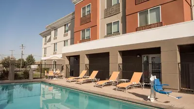 a swimming pool with lounge chairs and a building at Holiday Inn Express Porterville by IHG in Porterville