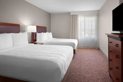 a hotel room with two beds and a flat screen tv at Larkspur Landing Extended Stay Suites Folsom in Folsom