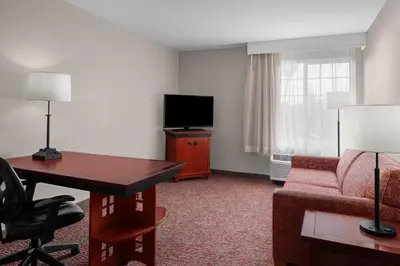 a hotel room with a desk and a couch and a television at Larkspur Landing Extended Stay Suites Folsom in Folsom