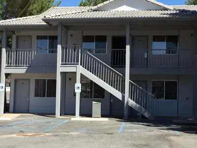 a apartment building with a staircase in a parking lot at Exchange Club Motel in Beatty