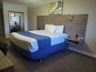 a hotel room with a large bed with blue sheets at Exchange Club Motel in Beatty