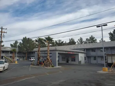a building with palm trees in a parking lot at Exchange Club Motel in Beatty