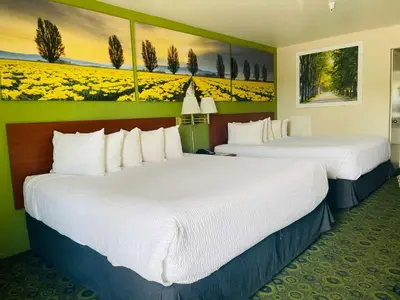 two beds in a hotel room with flowers on the walls at Days Inn by Wyndham Westley in Westley