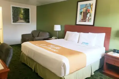 a hotel room with a large bed and a chair at Days Inn by Wyndham Westley in Westley