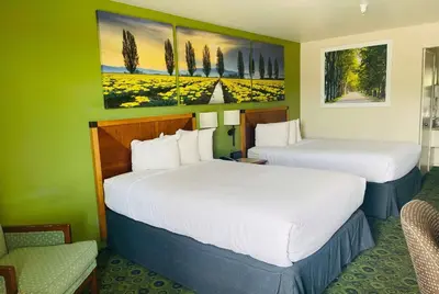 a hotel room with two beds and a chair at Days Inn by Wyndham Westley in Westley