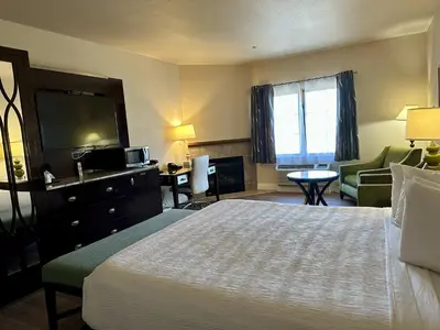 a hotel room with a bed and a living room at Rocklin Park Hotel, Trademark Collection by Wyndham in Rocklin