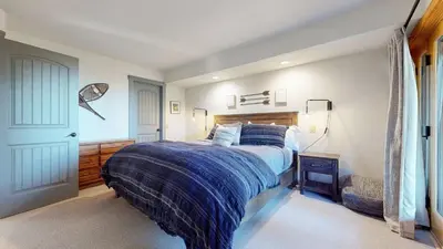 a bedroom with a bed with a blue comforter at Bridges Townhome #11 Townhouse in Mammoth Lakes