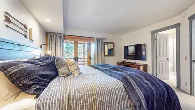 a bedroom with a bed with a blue comforter at Bridges Townhome #11 Townhouse in Mammoth Lakes