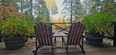 two chairs and a table on a deck with plants at Narrow Gauge Inn in Fish Camp