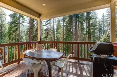 a screened in porch with a table and chairs and a grill at Pine Arbor Retreat in Yosemite West