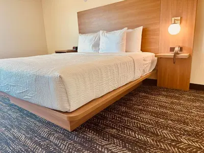 a bedroom with a large bed with a wooden headboard at Ramada by Wyndham Merced in Merced