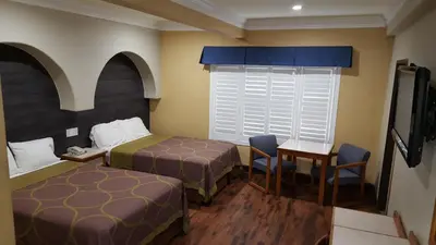 a hotel room with two beds and a table and chairs at Reedley Inn in Reedley