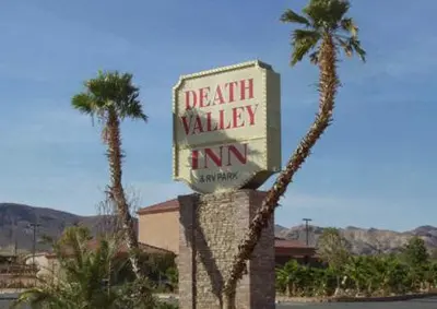 a sign for a death valley inn next to a palm tree at Death Valley Inn in Beatty